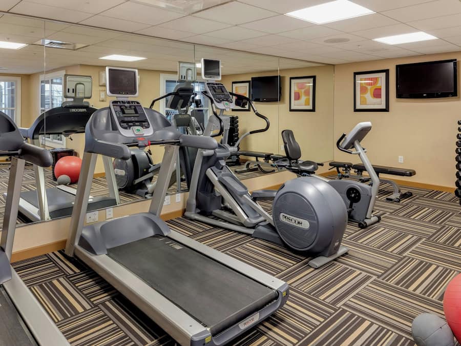 A gym with treadmills, elliptical machines, and exercise balls.