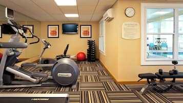 Un gimnasio con equipo de ejercicio, un reloj y una ventana con vistas.