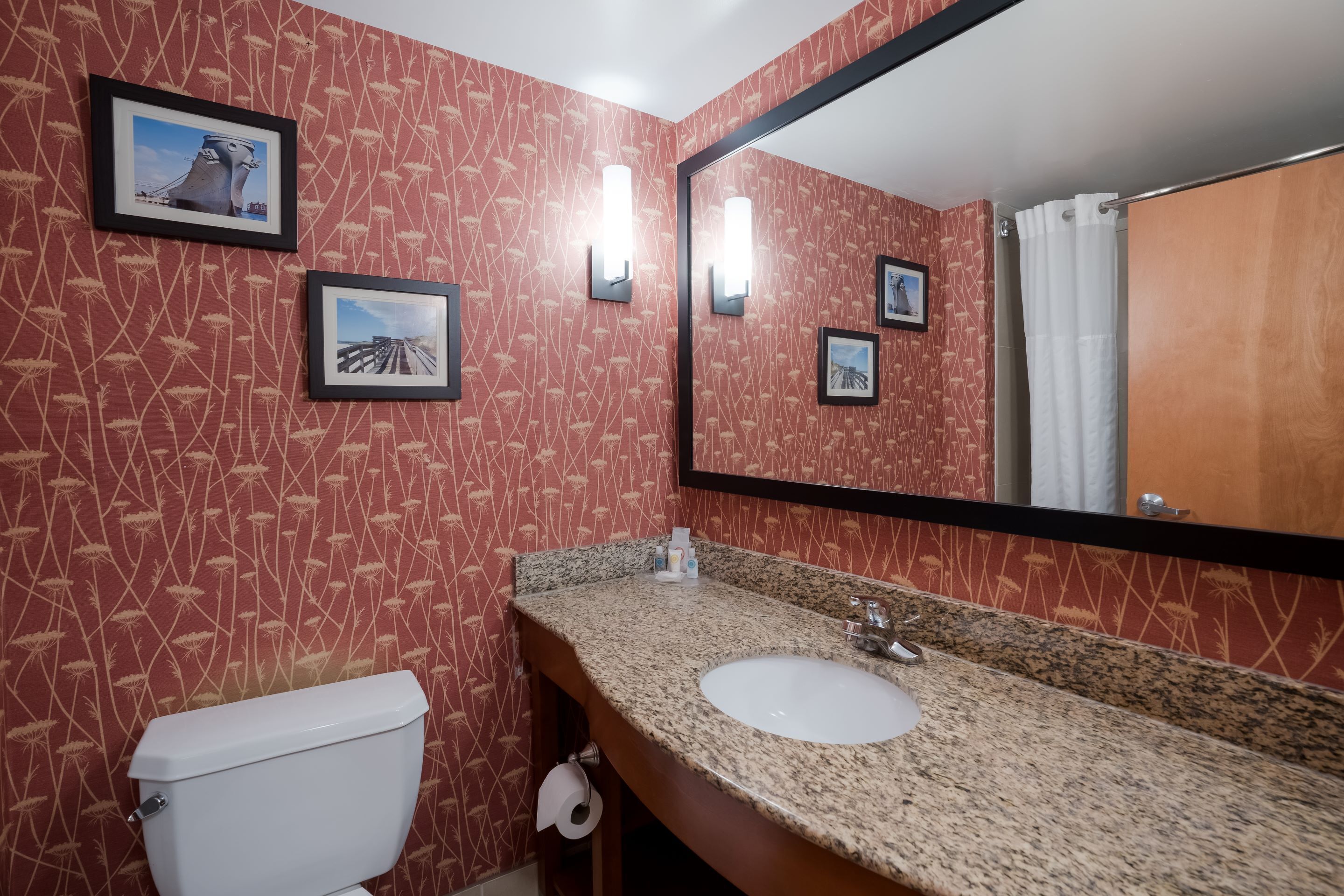A bathroom with a toilet, sink, and mirror.