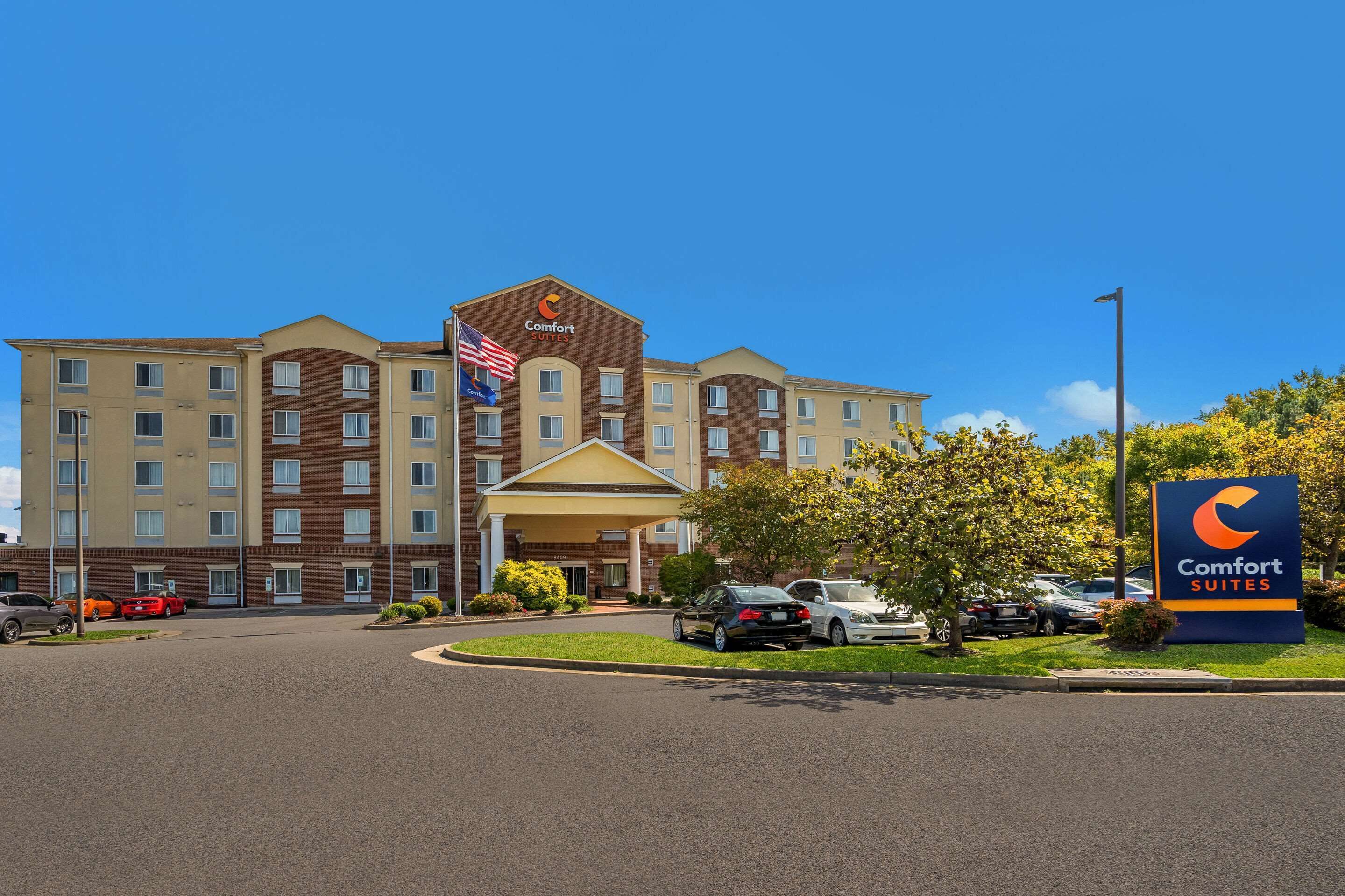 Ett Comfort Suites-hotell med en fasad av tegel, flera våningar och en central entré.