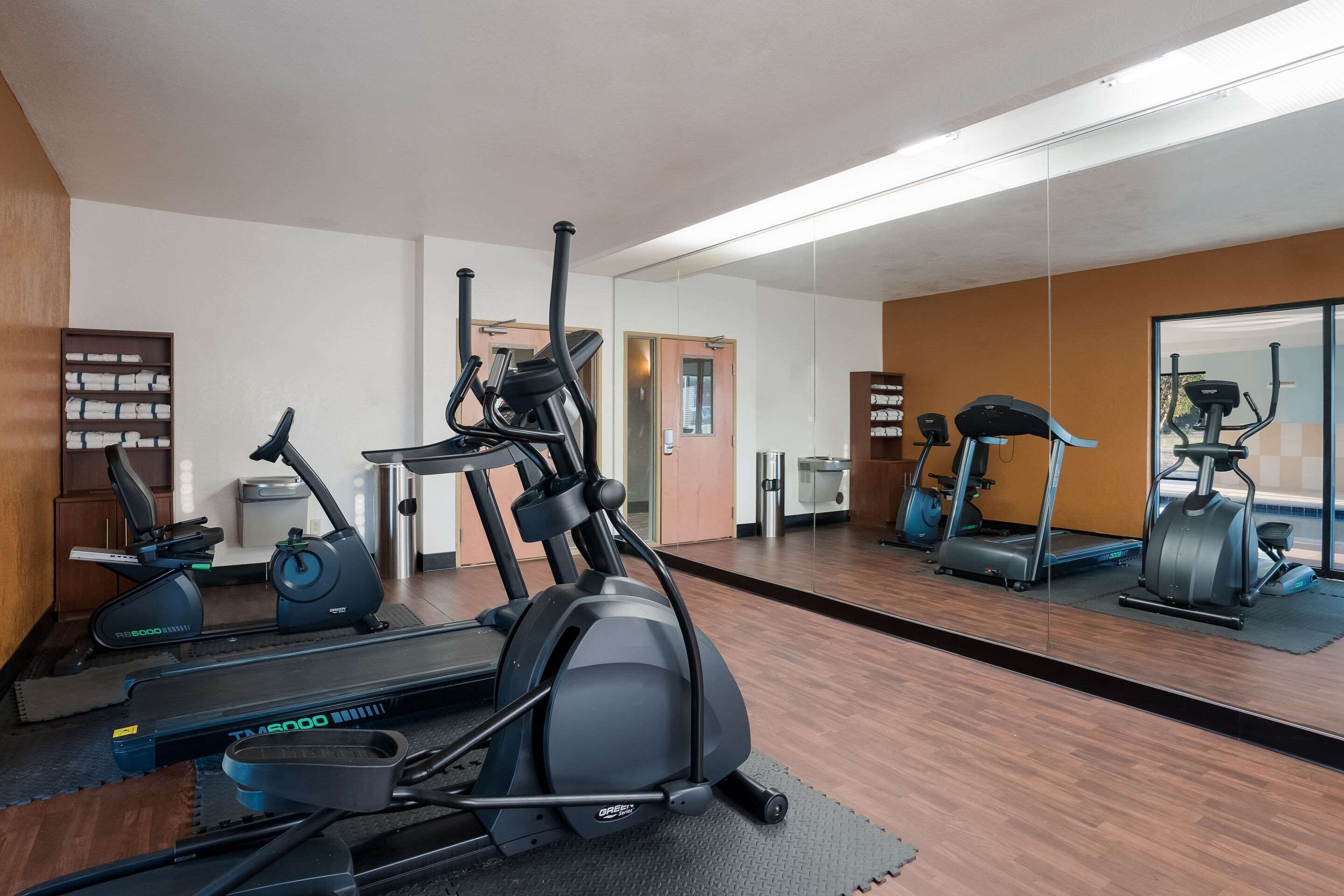 Un gimnasio con cintas de correr, elípticas y una bicicleta estática.