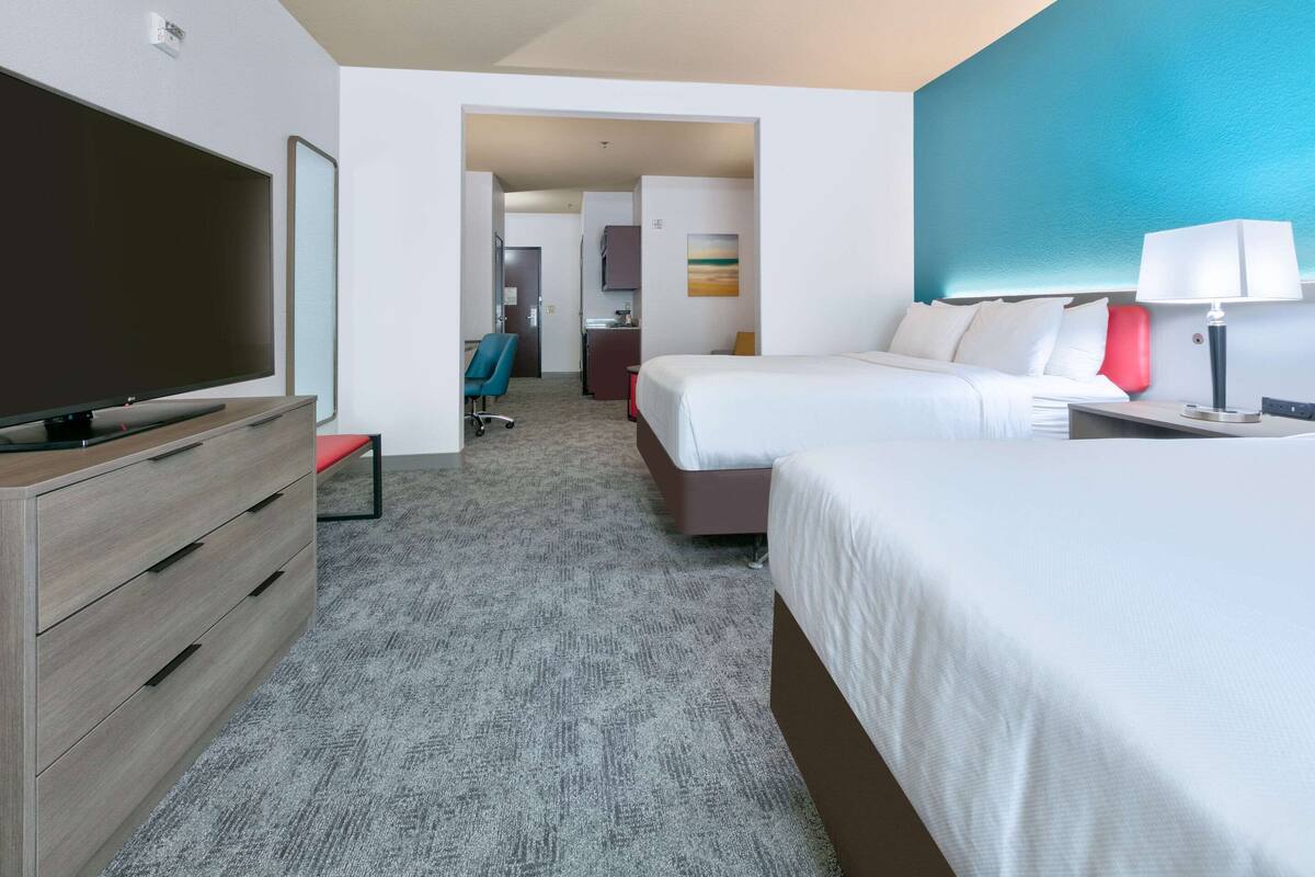 A hotel room with two beds, a TV, a desk, and a chair.