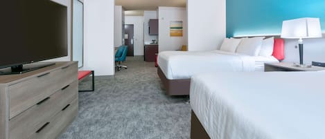 Ein Hotelzimmer mit zwei Betten, einem Fernseher, einem Schreibtisch und einem Stuhl.