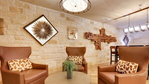 Una sala de estar moderna con sillones de cuero, una mesa de centro redonda y una pared de piedra con arte decorativo.