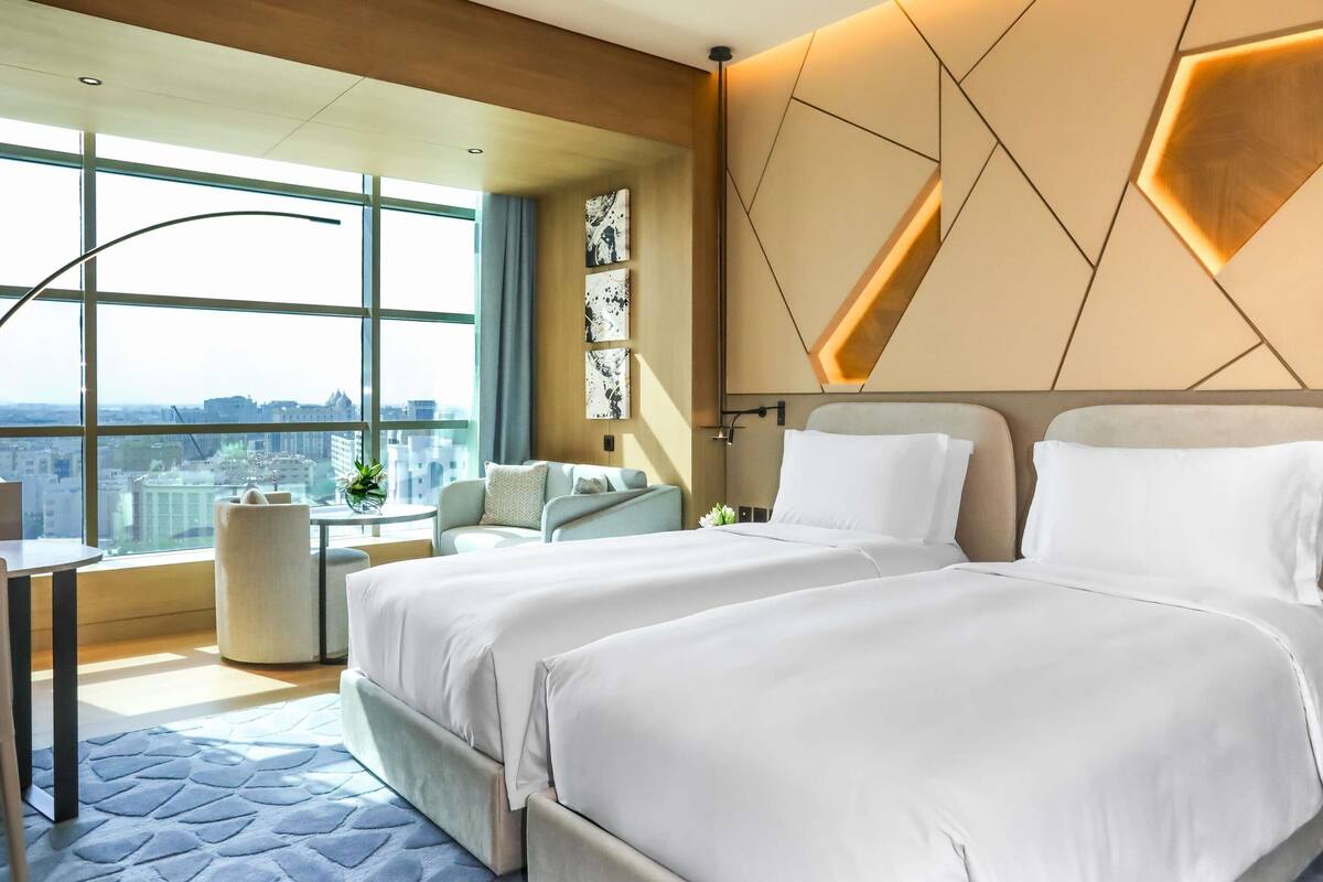 Quarto de hotel moderno com uma cama grande, uma escrivaninha e vista para a cidade.