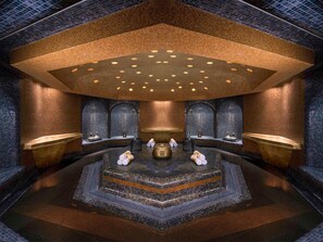 A luxurious spa room with a central hot tub, multiple seating areas, and a decorative ceiling. - La Cigale Hotel Managed by Accor (Doha)