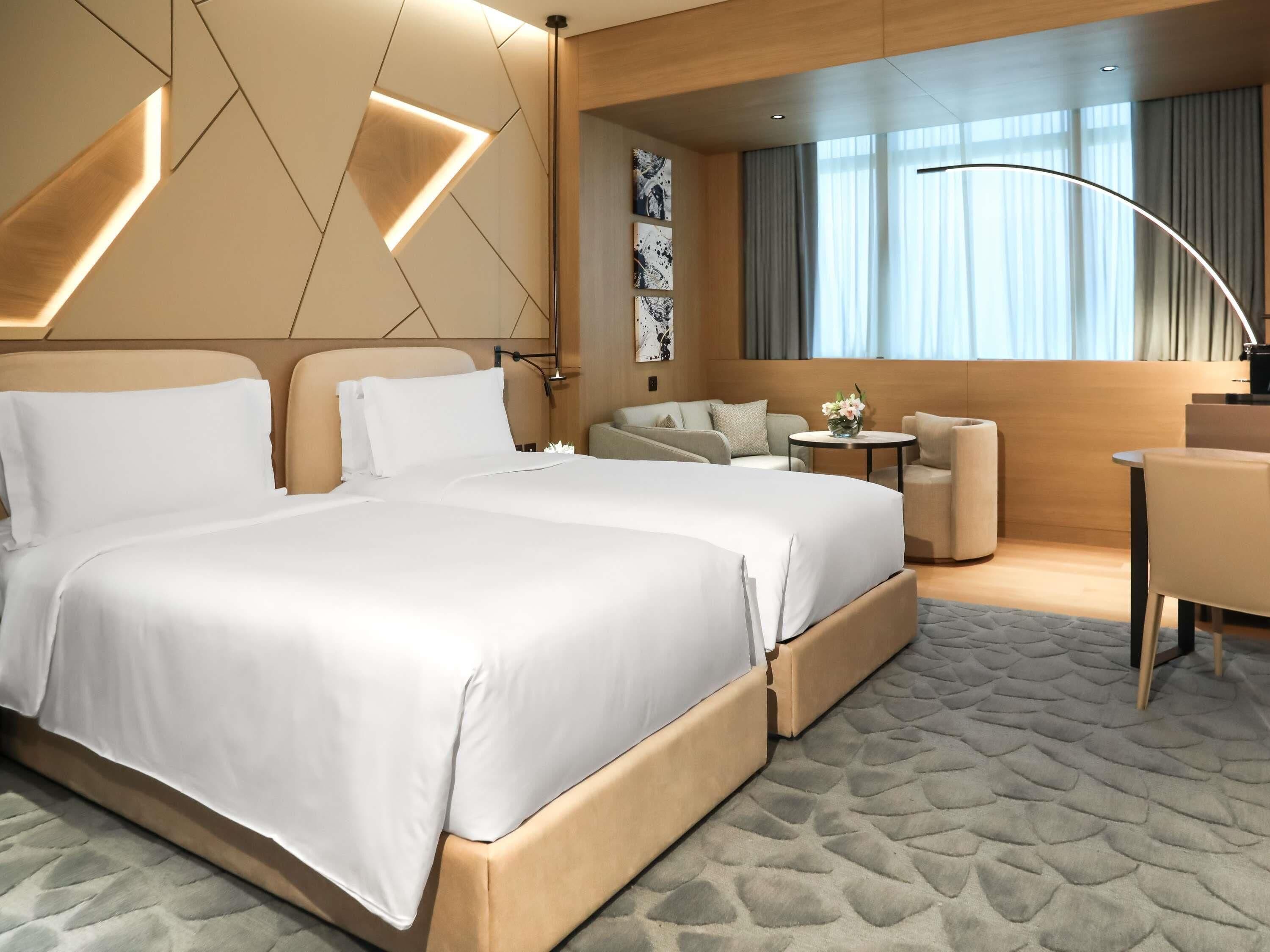 Una habitación de hotel moderna con una cama grande, un sofá, una pequeña mesa con flores y un escritorio.