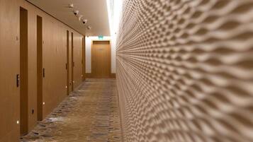 Un pasillo de hotel con un papel tapiz decorativo, puertas de madera y piso de baldosas.