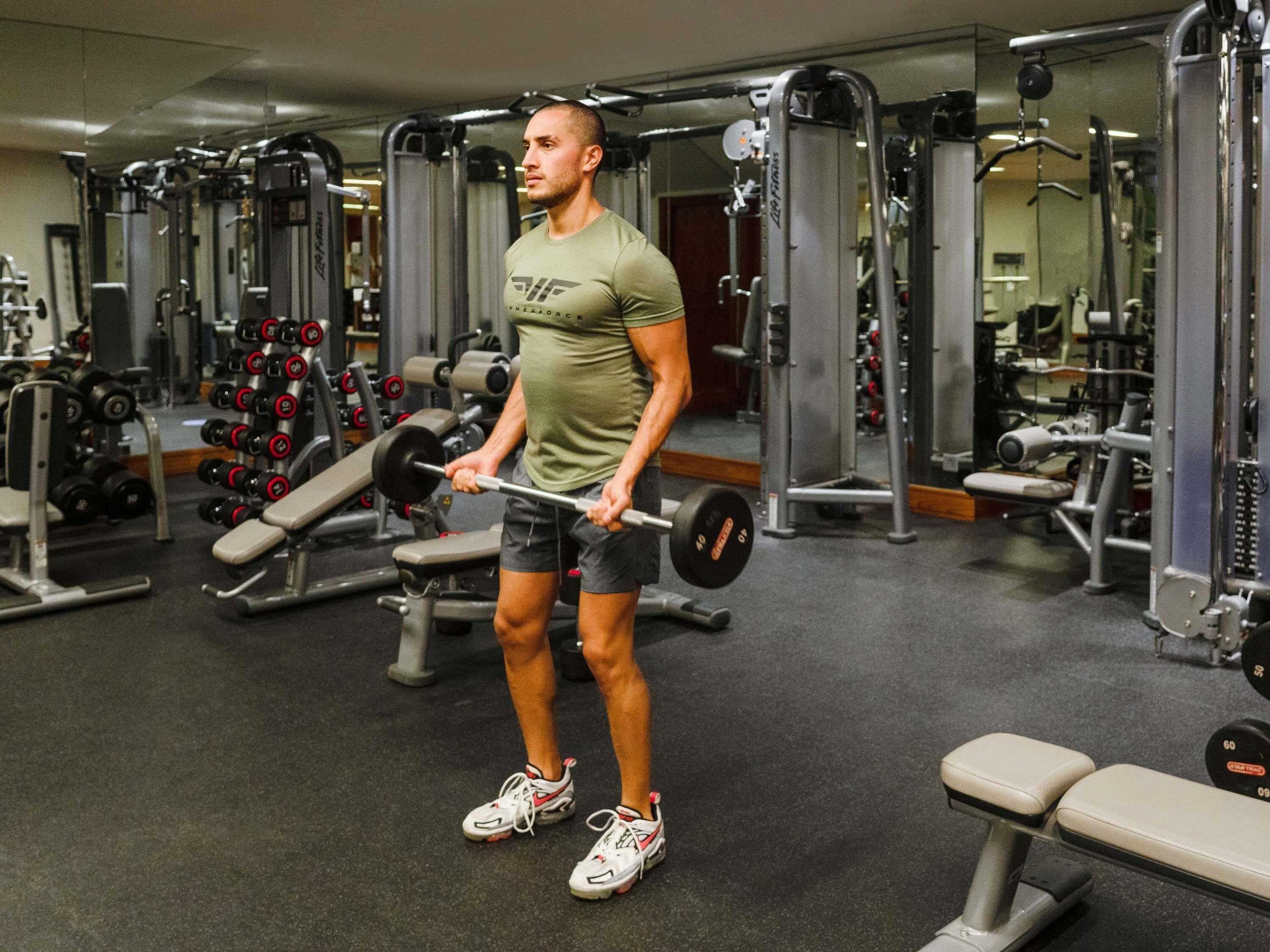 A gym with weightlifting equipment, benches, and a mirror.