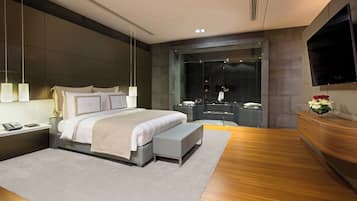 A modern bedroom with a large bed, bedside tables, a bench, a TV, and a glass shower enclosure.