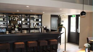 Un espace bar avec des tabourets, un comptoir et des étagères remplies de bouteilles et de verres.