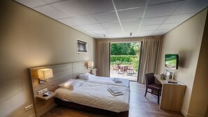 Une chambre d’hôtel avec un lit double, des tables de chevet avec des lampes, un bureau avec une chaise et une vue sur l’extérieur.