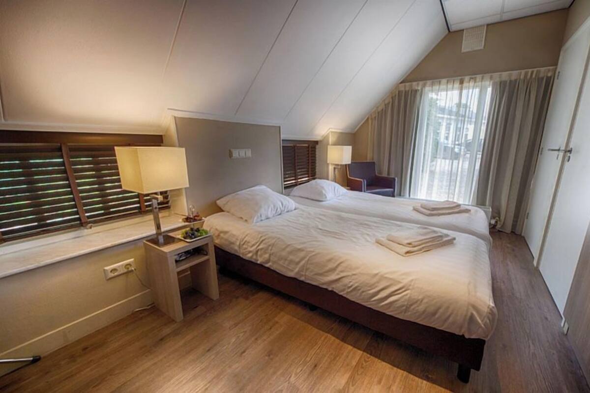 Een hotelkamer met een tweepersoonsbed, nachtkastjes, een lamp, een stoel en een kledingkast.