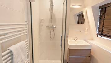 A modern bathroom with a glass-enclosed shower, a white sink, and a toilet.