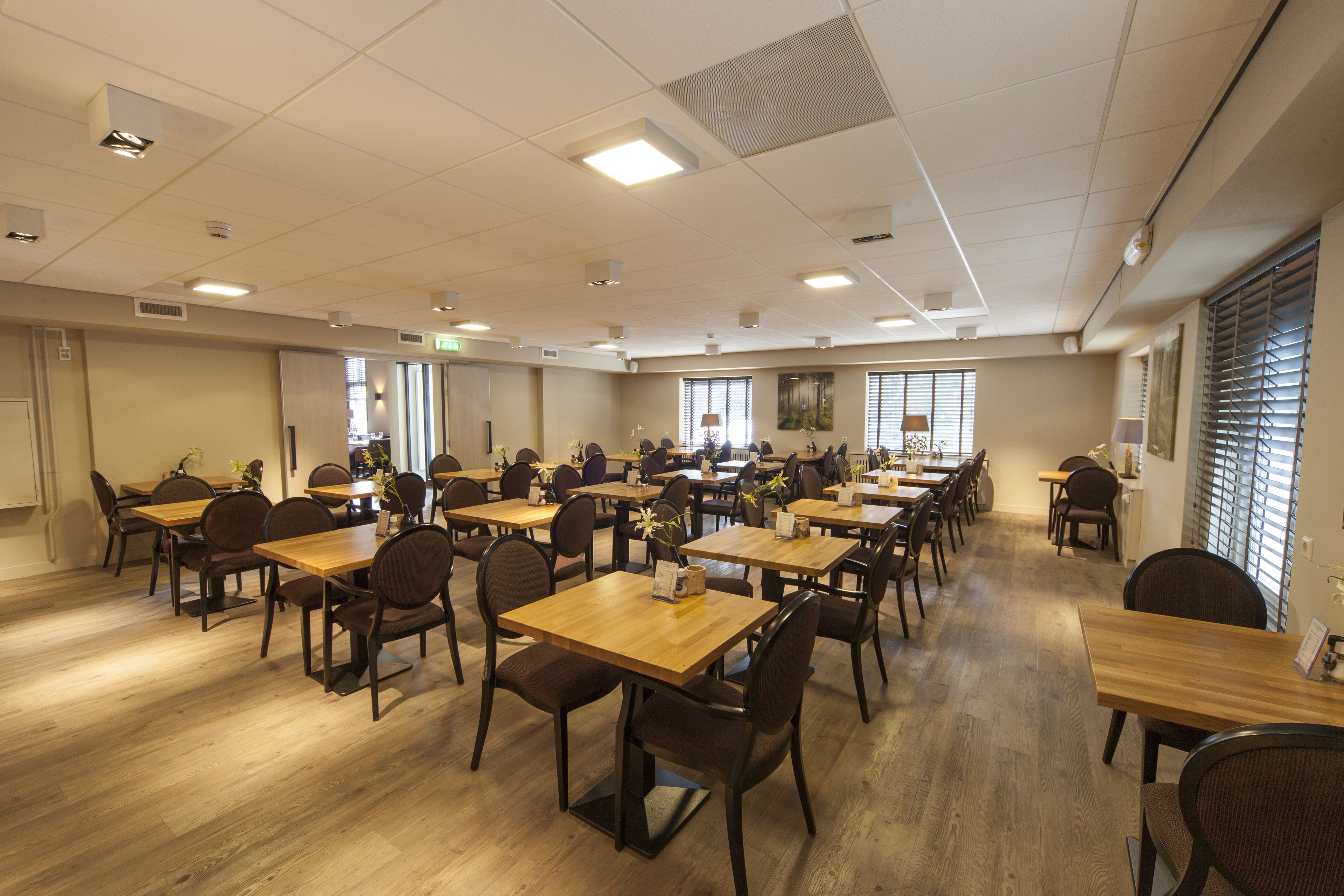 A spacious dining area with multiple tables and chairs, arranged in rows.