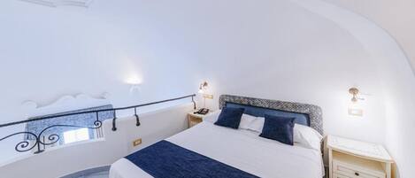 A bedroom with a bed, bedside tables, and a balcony railing.