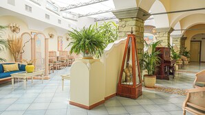 A spacious lobby with high ceilings, a central fountain, and multiple seating areas. - Hotel Nettuno (Forio)