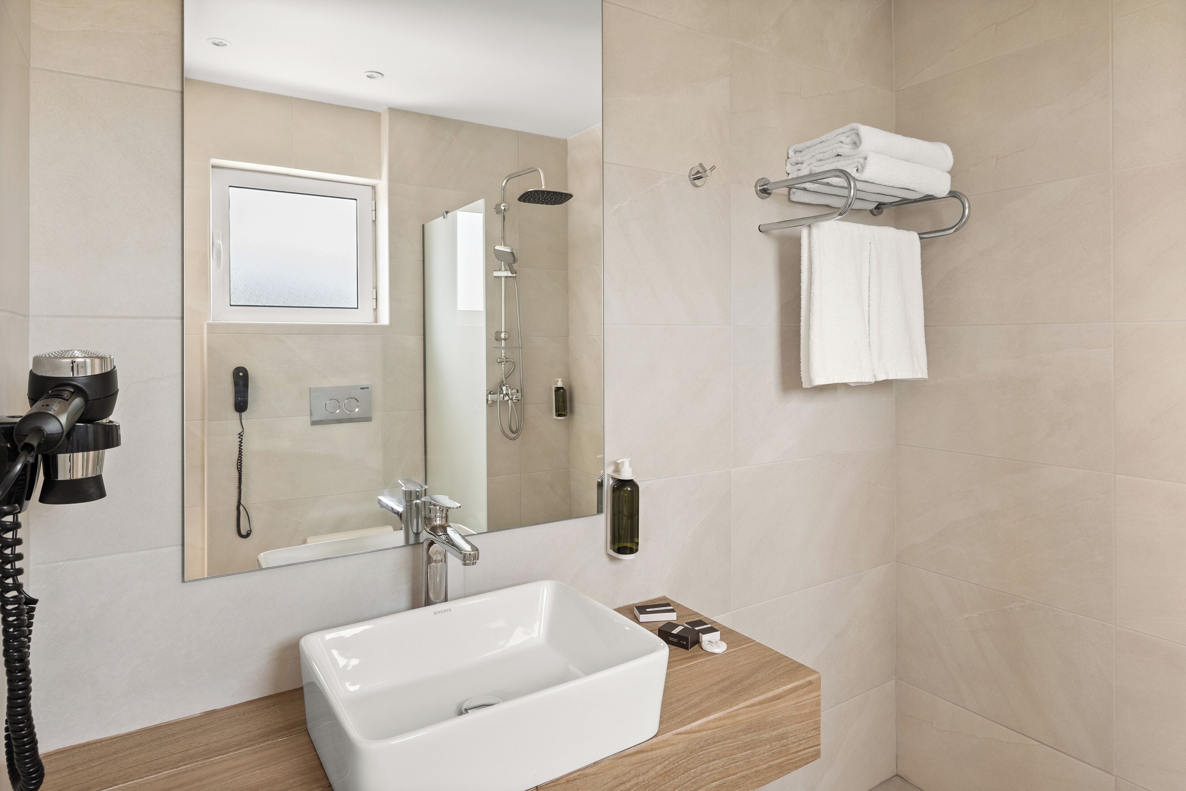 A modern bathroom with a large mirror, a sink, a shower, and a towel rack.
