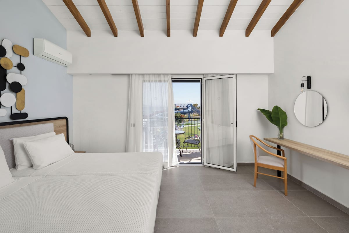 A modern bedroom with a bed, a desk, a chair, and a balcony with a view.