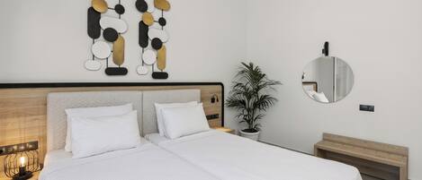 A modern bedroom with a large bed, bedside tables, a wall-mounted mirror, and a decorative wall piece.