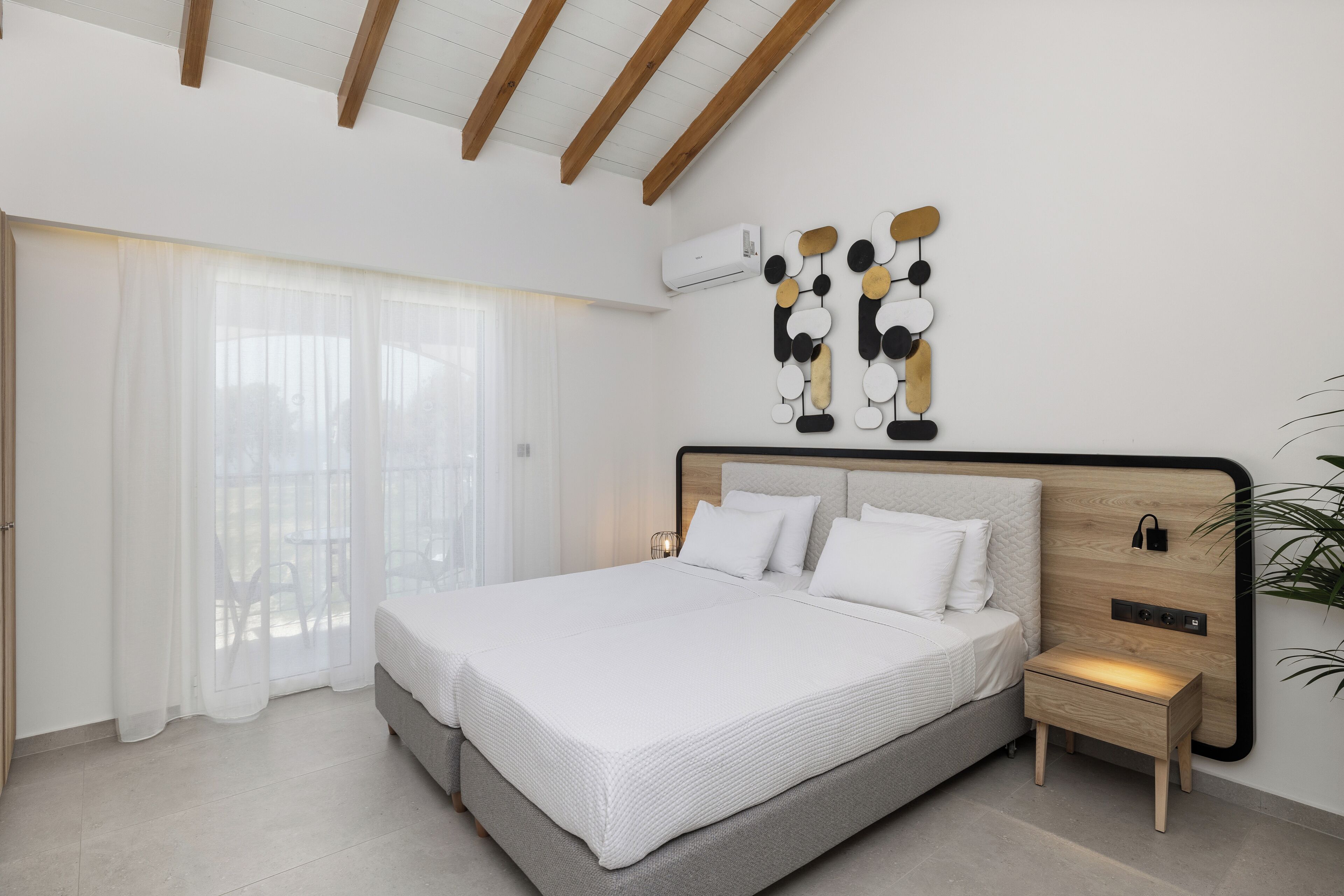 Un dormitorio moderno con una cama grande, una mesita de noche y un aire acondicionado instalado en la pared.