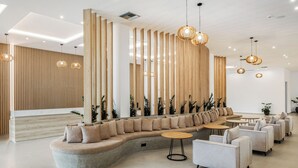 Una moderna zona de recepción con una distribución de asientos curva, paneles de madera e iluminación colgante.