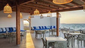 Un área de estar al aire libre con muebles de mimbre e iluminación colgante, con vista al mar.