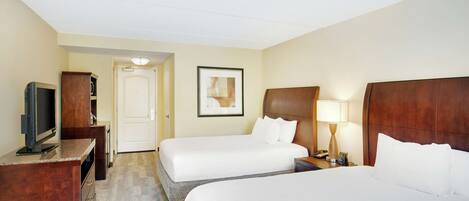 A hotel room with two beds, a TV, a desk, and a door.