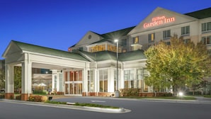 Un Hilton Garden Inn con entrada cubierta, ventanas amplias y fachada bien iluminada.