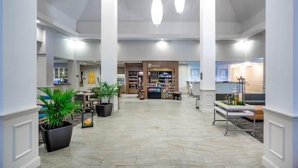 Un vestíbulo amplio con una zona de estar central, una cafetería y una recepción.