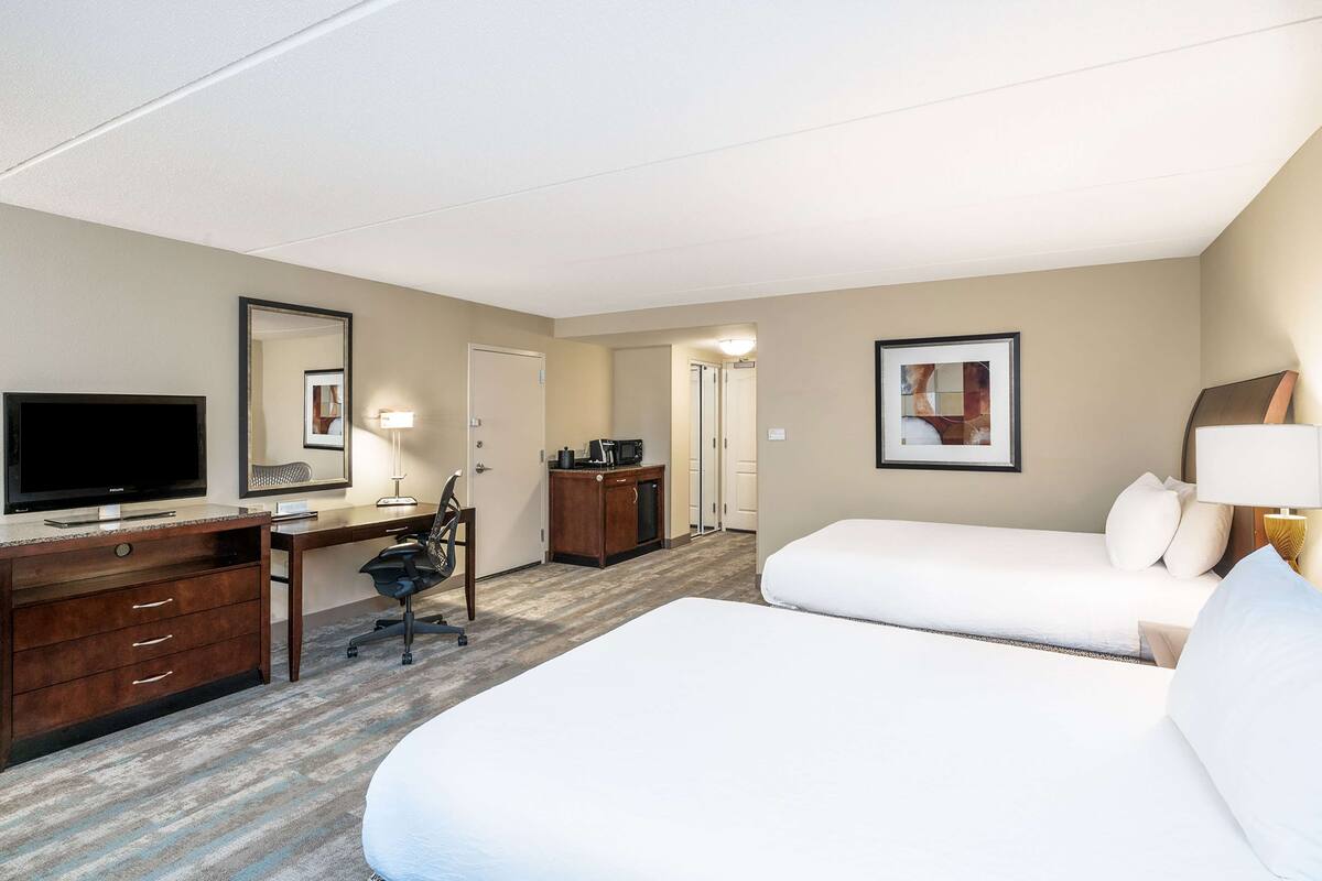 Een hotelkamer met een bed, bureau, stoel, televisie en een kleine kitchenette.