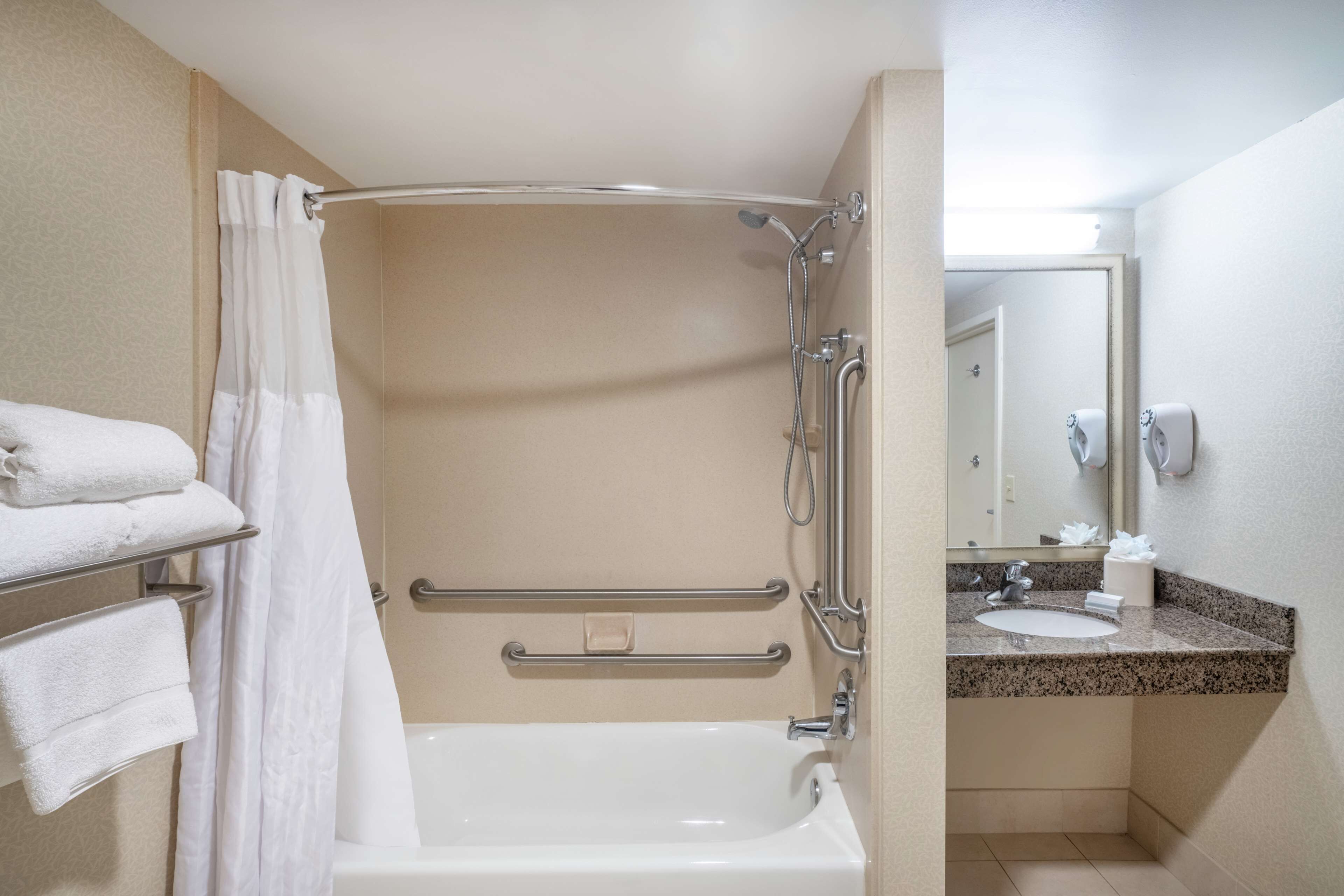 A bathroom with a bathtub, a shower, a sink, and a mirror.