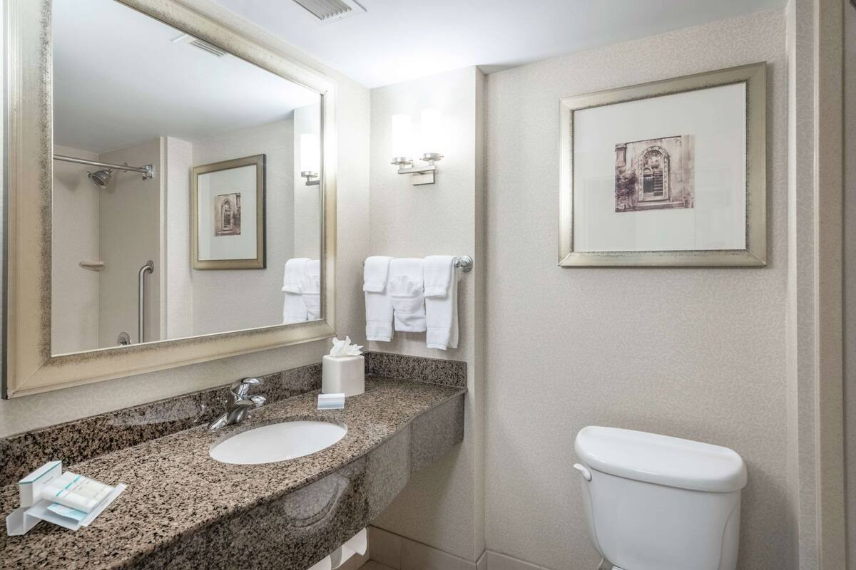 Een badkamer met een wastafel, spiegel, handdoekrek en toilet.