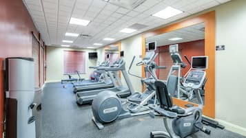 A gym with treadmills, elliptical machines, and a water dispenser.