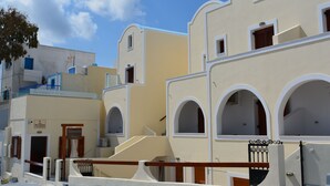 A row of white buildings with arched windows and balconies, labeled "Anemomilos Suites." - Anemomilos Suites (Santorini)
