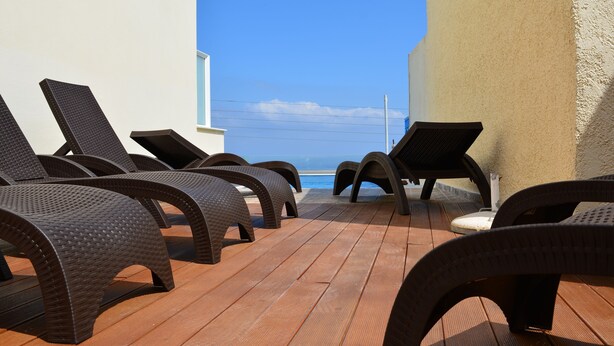 A deck with lounge chairs facing a pool and a clear view of the sky. - Anemomilos Suites (Santorini)