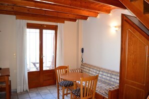 Una mesa de madera para comer con sillas, un sofá a cuadros y una puerta de madera.