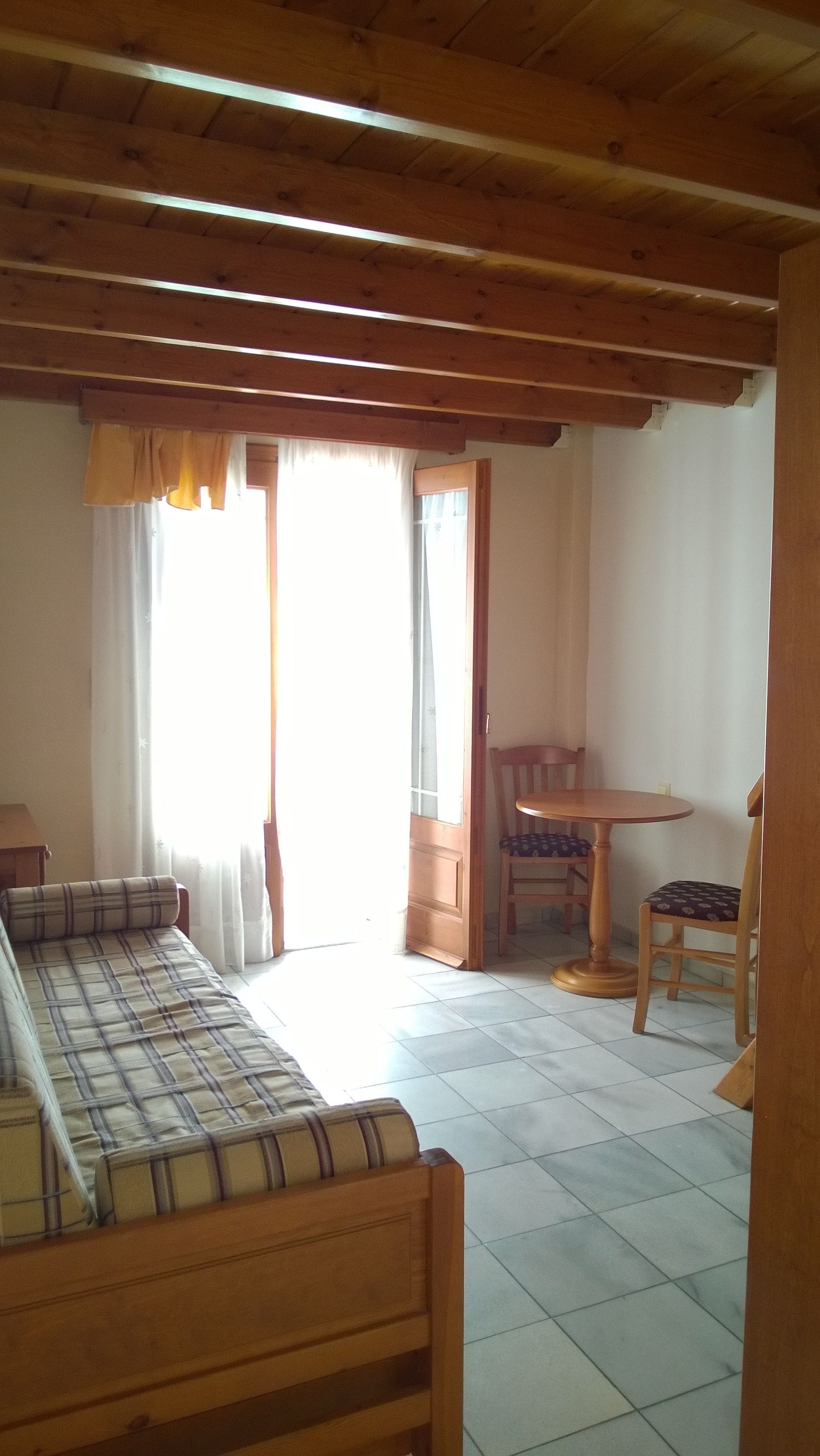 A room with a wooden ceiling, a sofa, a small table, and a chair.
