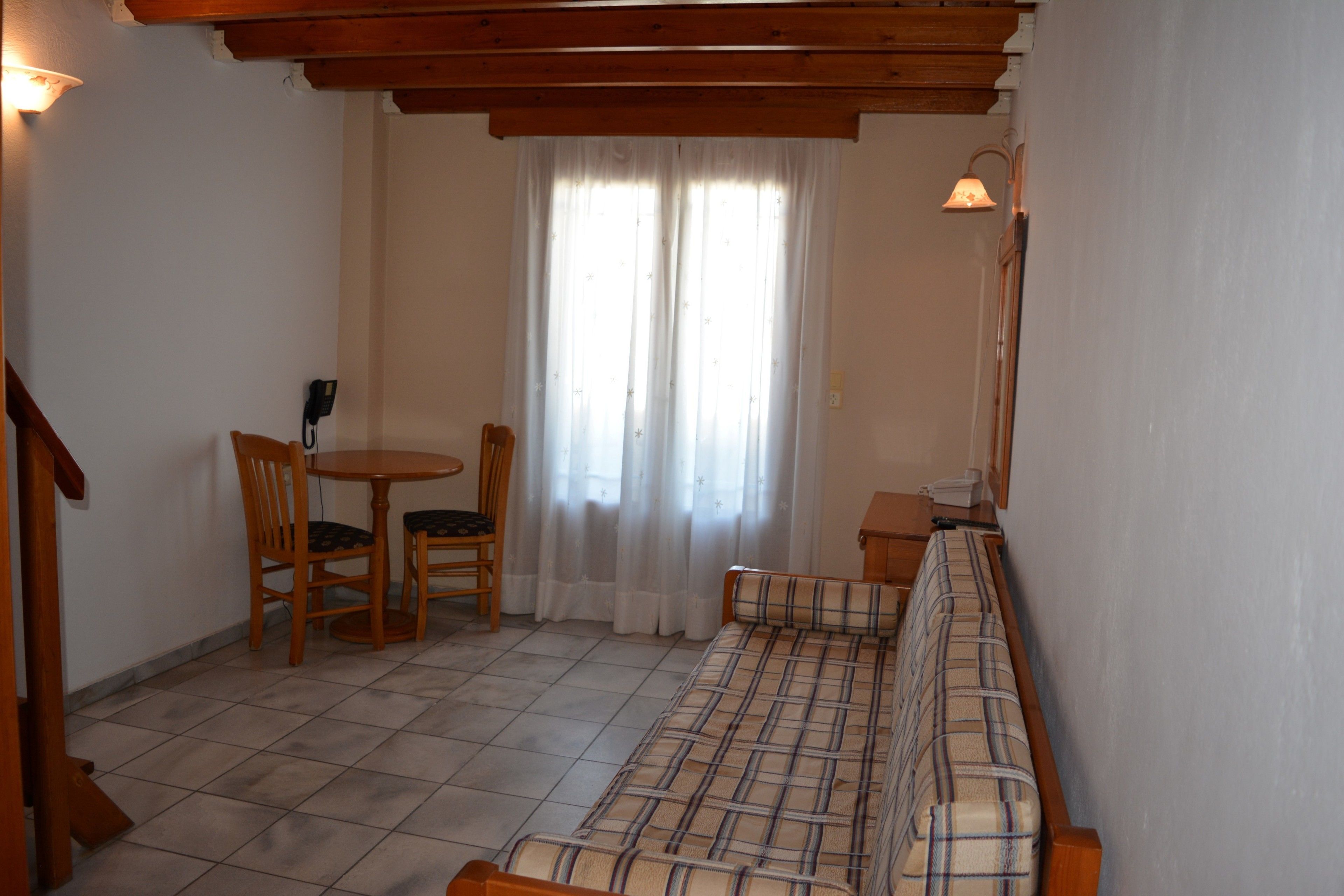 Una habitación con sofá, una mesita, dos sillas, una lámpara y un teléfono.