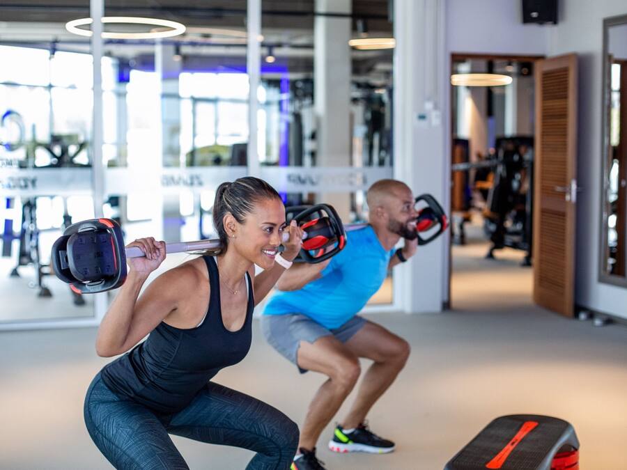 Un gimnasio con equipo de levantamiento de pesas y espejos.