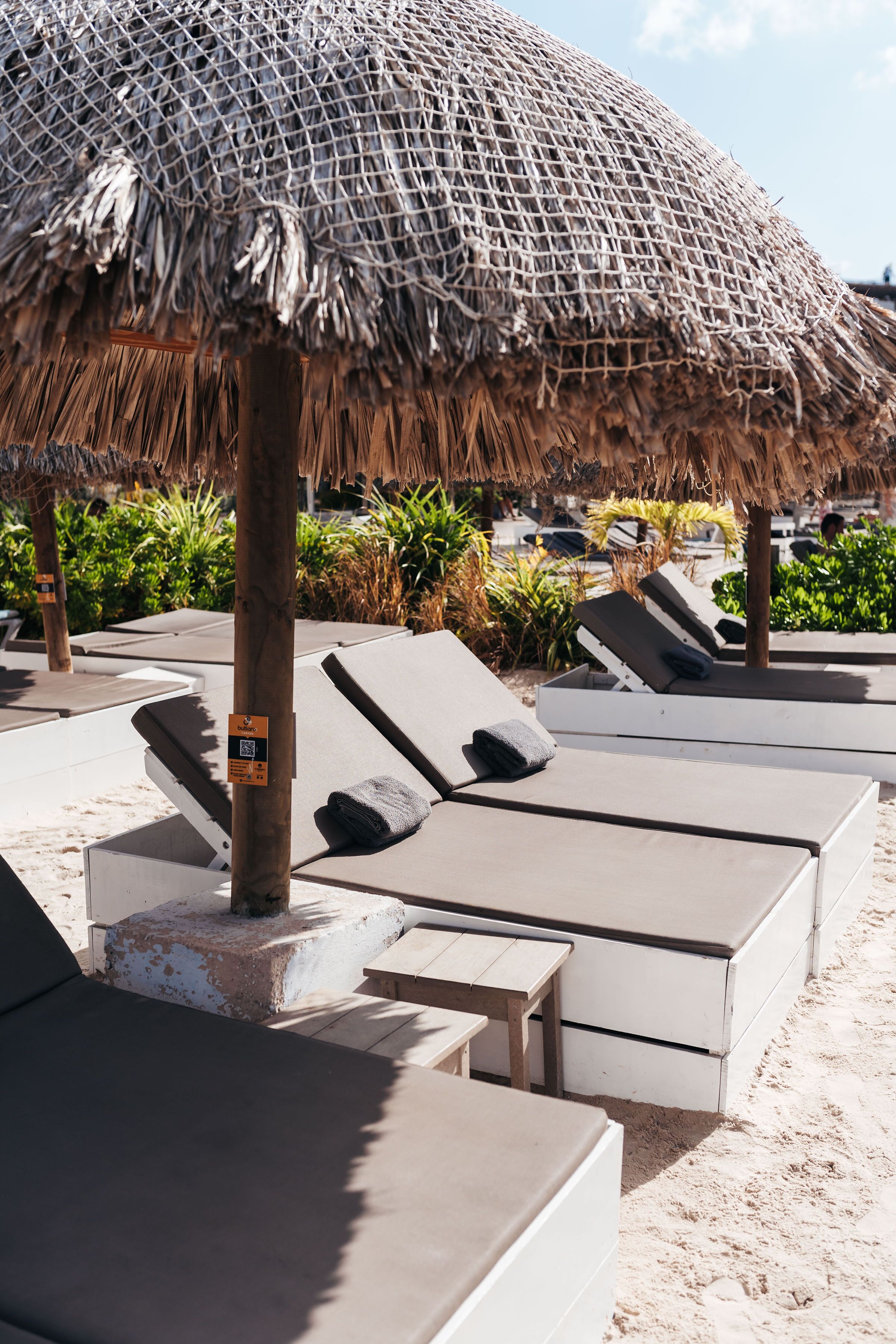 A beachside lounge area with sun loungers and a thatched umbrella.