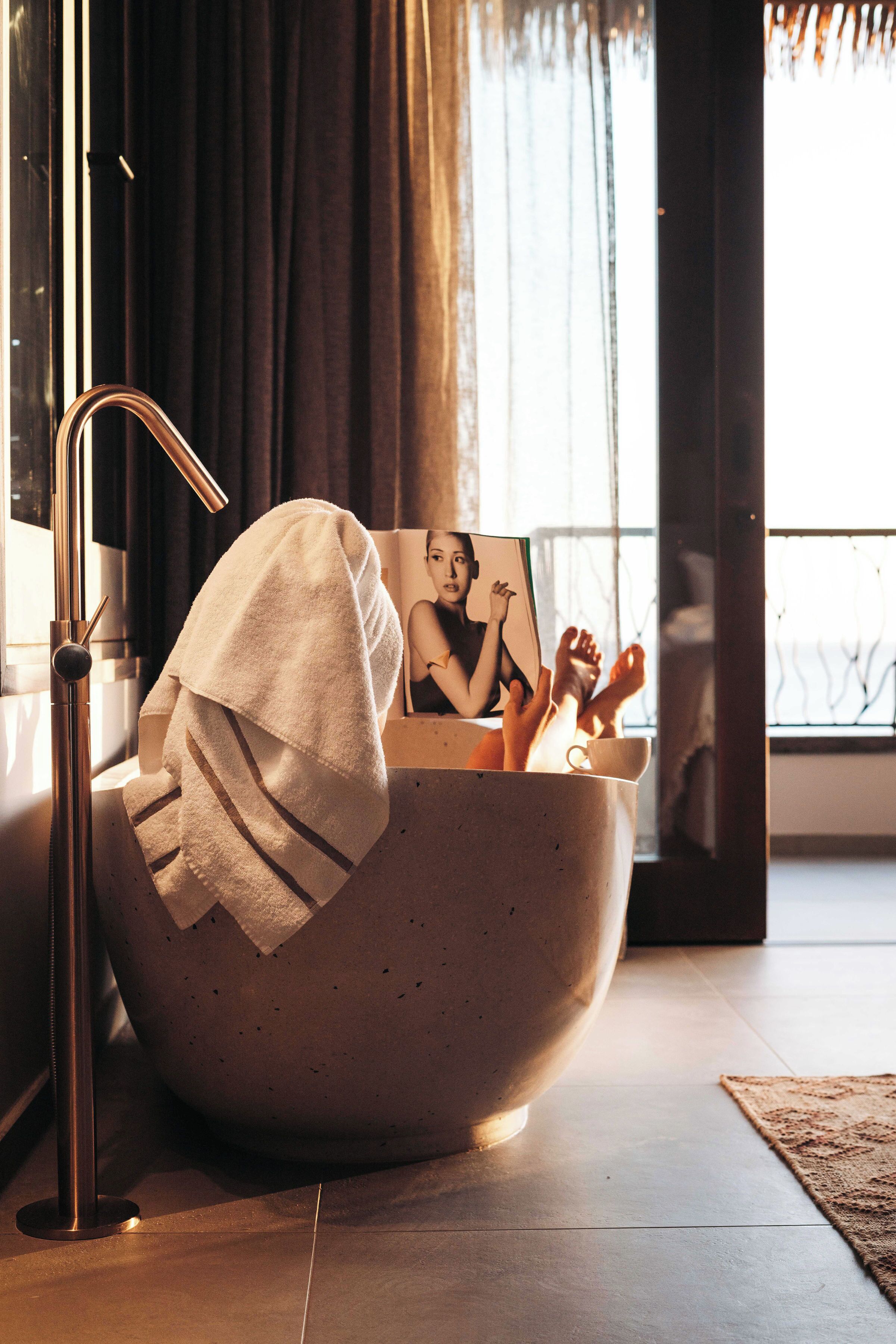 A modern bathroom with a large bathtub, a towel, and a framed photo.