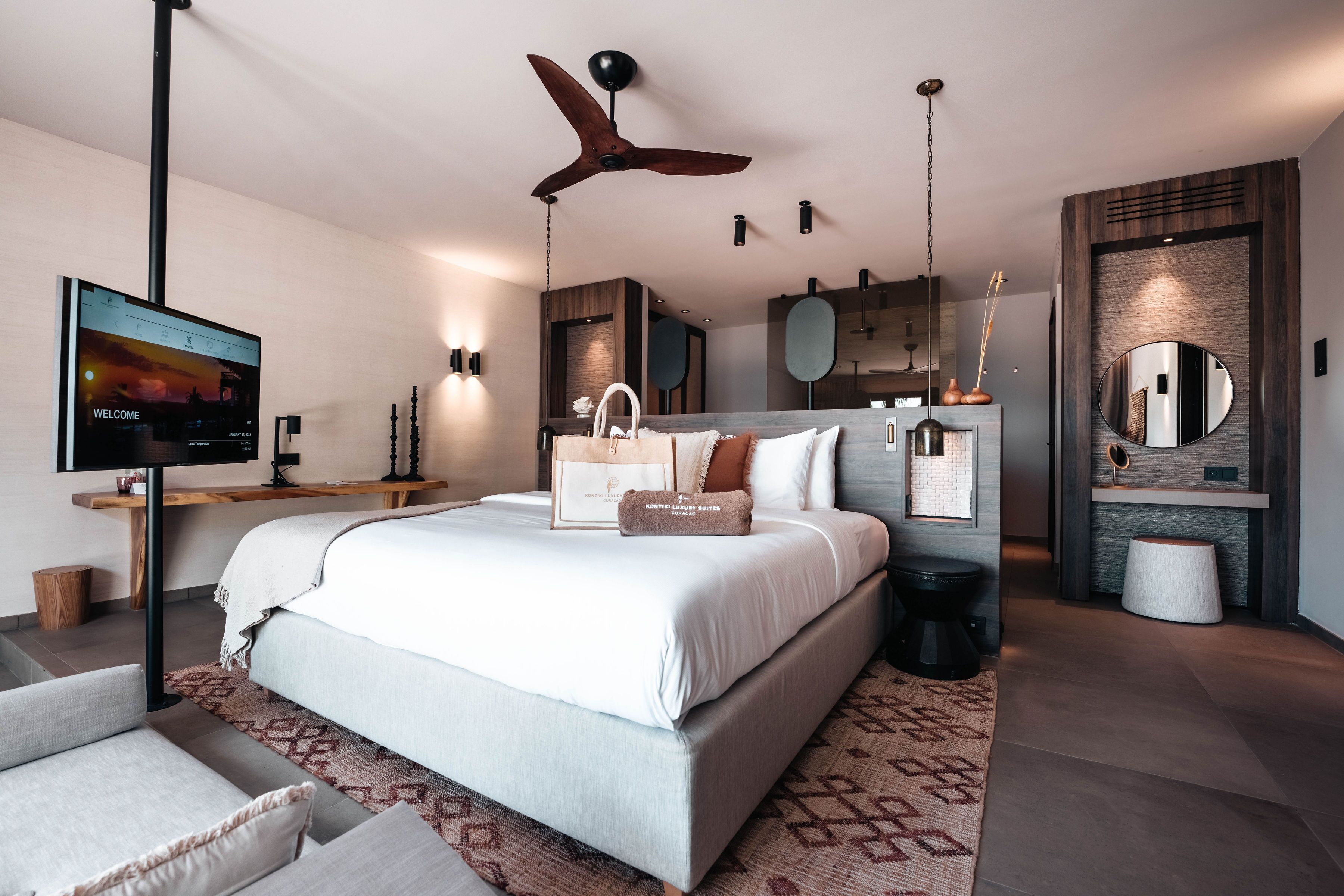 Un dormitorio moderno con una cama grande, ventilador de techo, televisión y pared decorativa de madera.
