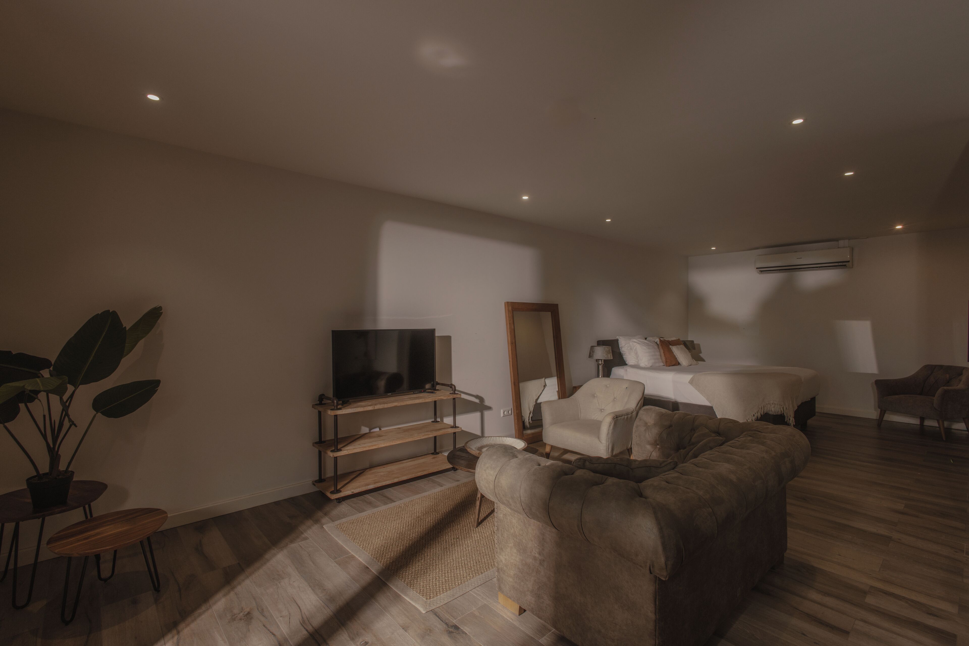 A modern living room with a sofa, TV, and a large mirror.