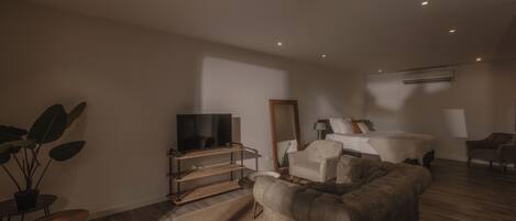 A modern living room with a sofa, TV, and a large mirror.