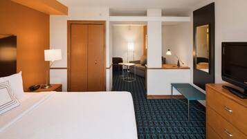 A hotel room with a bed, a desk, a chair, a TV, and a wardrobe.