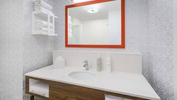 A bathroom with a white sink, wooden vanity, and a mirror with a red frame.
