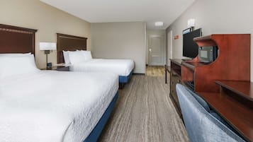 Une chambre d’hôtel avec deux lits, un bureau avec une télévision et une porte de salle de bain.