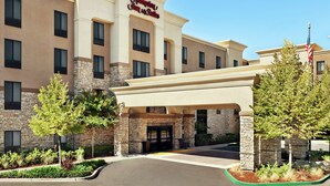 A Hampton Inn & Suites building with a stone facade, a covered entrance, and a flag. - Hampton Inn & Suites West Sacramento (West Sacramento)