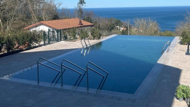 Une piscine avec vue sur la mer, un petit bâtiment et un ciel dégagé.